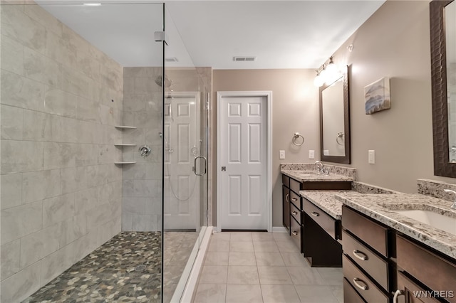 bathroom featuring a tile shower, tile patterned floors, and two vanities