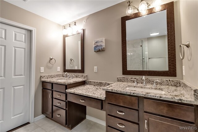 bathroom with vanity, tiled shower, tile patterned flooring, and baseboards