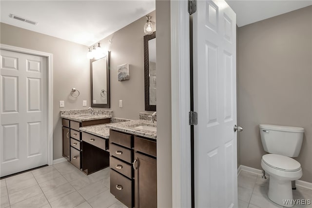 bathroom with tile patterned floors, double vanity, baseboards, and toilet