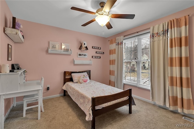 bedroom featuring light colored carpet, baseboards, an office area, and a ceiling fan