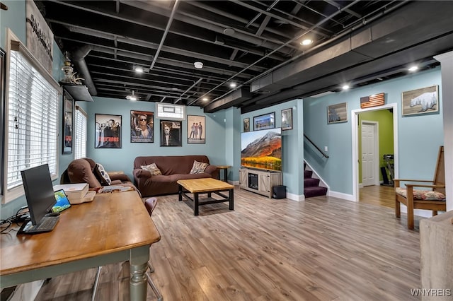 living area with wood finished floors, stairway, and baseboards