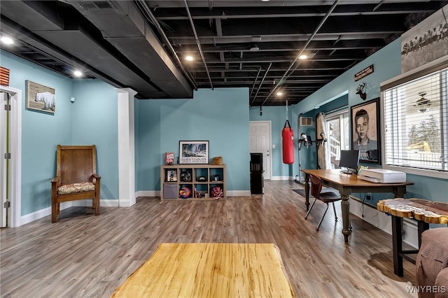 rec room featuring wood finished floors, baseboards, and an office area