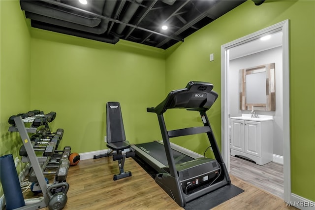 workout room with wood finished floors, baseboards, and a sink