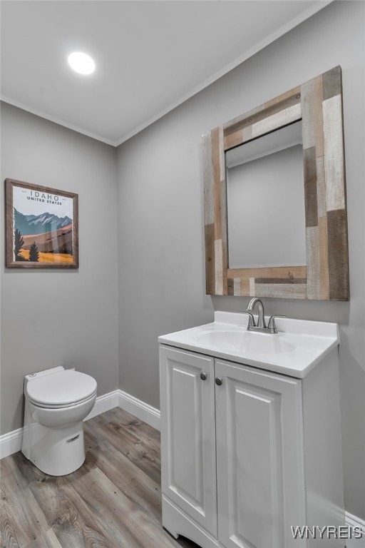 bathroom with wood finished floors, toilet, vanity, and baseboards