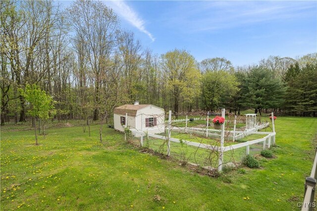 view of yard with an outbuilding, a garden, a wooded view, and a shed