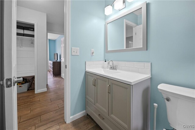 bathroom featuring baseboards, wood finished floors, toilet, and vanity