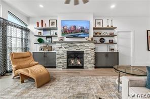 living room featuring a ceiling fan, a stone fireplace, and recessed lighting