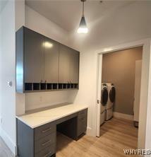 mudroom with independent washer and dryer, light wood-type flooring, and baseboards