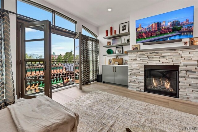 living room with wood finished floors, recessed lighting, and a stone fireplace