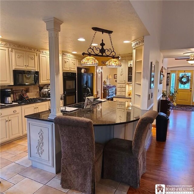 384 Flickerwood Rd, Kane-Borough, PA 16735 - kitchen with black appliances, decorative columns, cream cabinets, a large island, and a breakfast bar