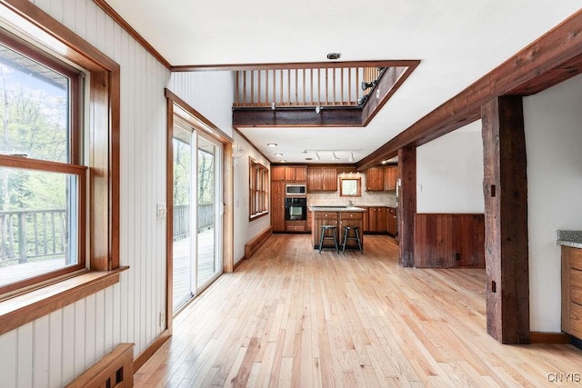 1826 Cardner Rd, Fabius, NY 13122 - kitchen featuring oven, stainless steel microwave, light wood-style floors, brown cabinets, and backsplash