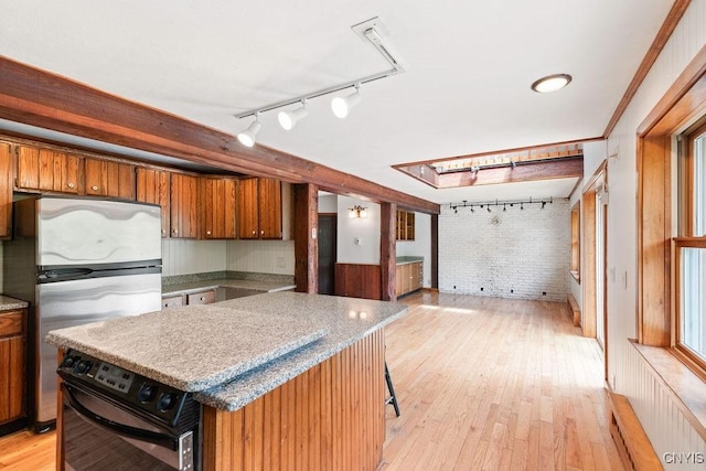 1826 Cardner Rd, Fabius, NY 13122 - kitchen featuring freestanding refrigerator, rail lighting, wall oven, brick wall, and brown cabinetry