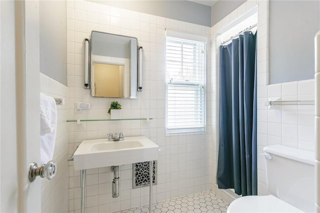 bathroom featuring tile walls, toilet, tiled shower, and plenty of natural light