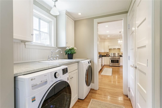 laundry room with cabinet space, washing machine and dryer, light wood-style flooring, crown molding, and recessed lighting