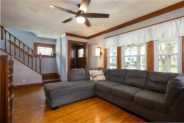 living area featuring baseboards, wood finished floors, stairs, and ceiling fan