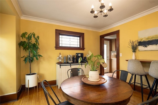 dining area with wood finished floors, a chandelier, crown molding, and baseboards