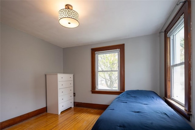 bedroom featuring light wood finished floors and baseboards
