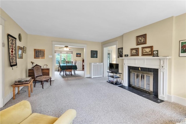 carpeted living area with radiator heating unit, a fireplace, baseboards, and a ceiling fan