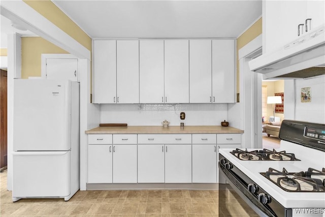 kitchen featuring freestanding refrigerator, gas range oven, under cabinet range hood, and light countertops