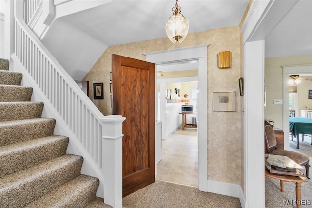 stairs featuring a ceiling fan and carpet flooring
