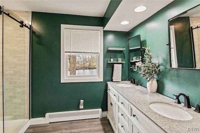 545 County Route 54, Schroeppel, NY 13132 - bathroom with baseboard heating, a shower stall, wood finished floors, baseboards, and double vanity