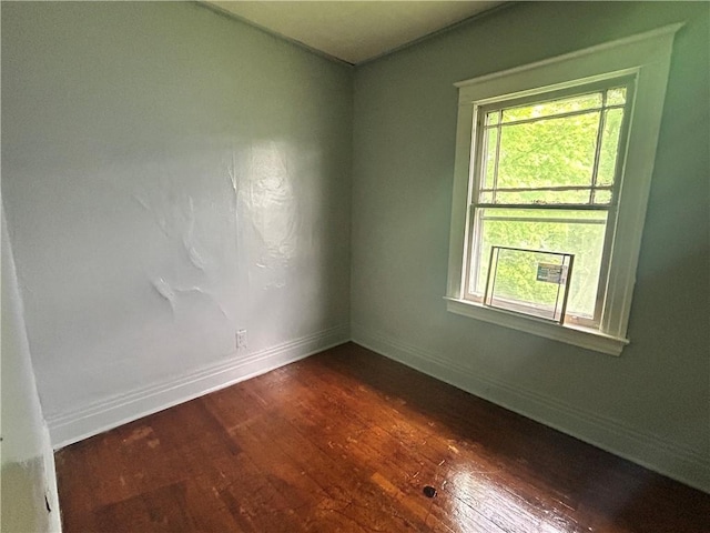 unfurnished room featuring dark wood-style flooring and baseboards