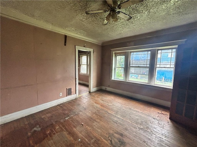 empty room featuring wood-type flooring, baseboards, a ceiling fan, and a textured ceiling