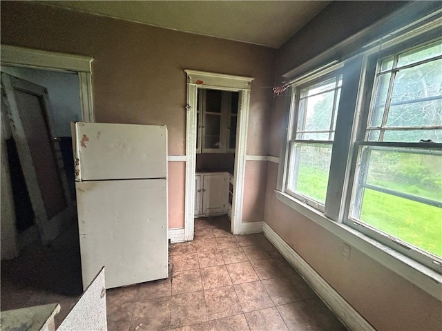 interior space with freestanding refrigerator, baseboards, and tile patterned flooring