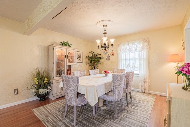 1430 Erie Station Rd, Henrietta, NY 14467 - dining space featuring a chandelier, wood finished floors, baseboards, and a textured ceiling