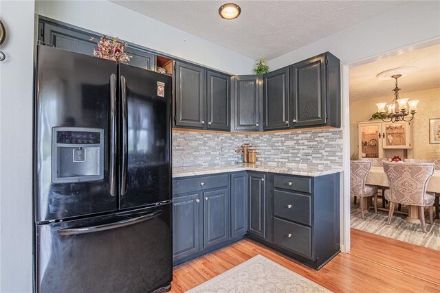 1430 Erie Station Rd, Henrietta, NY 14467 - kitchen with black refrigerator with ice dispenser, a chandelier, light wood finished floors, tasteful backsplash, and light stone countertops