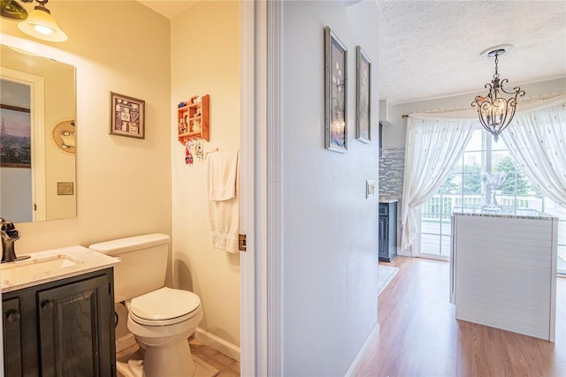 1430 Erie Station Rd, Henrietta, NY 14467 - half bathroom featuring toilet, wood finished floors, vanity, a chandelier, and a textured ceiling
