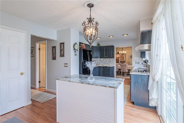 1430 Erie Station Rd, Henrietta, NY 14467 - kitchen featuring black fridge, a chandelier, decorative backsplash, a kitchen island, and under cabinet range hood