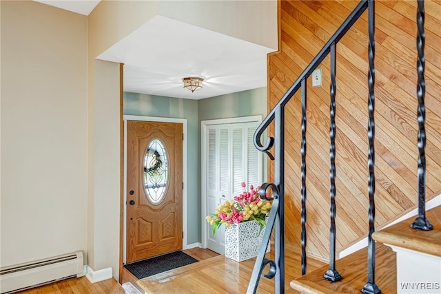 foyer featuring baseboard heating, baseboards, and wood finished floors