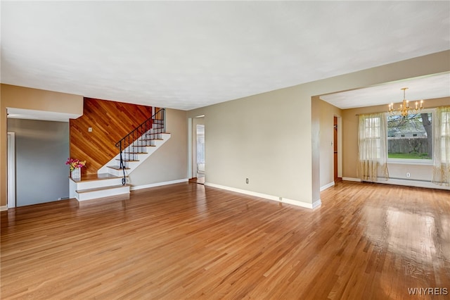 unfurnished living room featuring a chandelier, light wood-type flooring, stairs, baseboards, and a baseboard heating unit