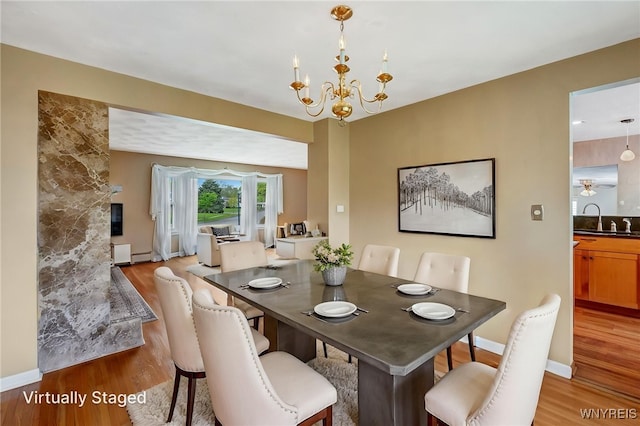 dining space with light wood finished floors, a chandelier, and baseboards