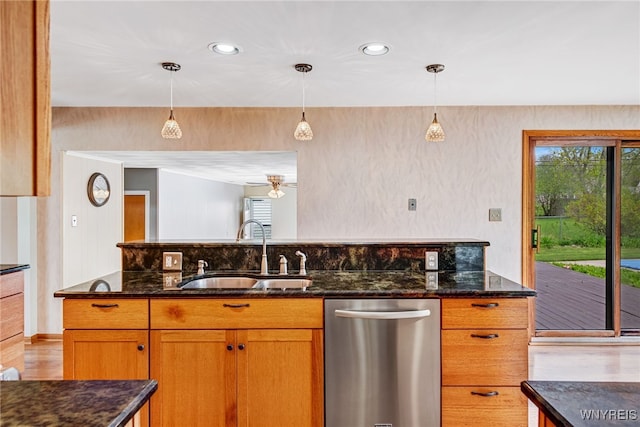 kitchen with stainless steel dishwasher, a sink, plenty of natural light, dark stone counters, and recessed lighting