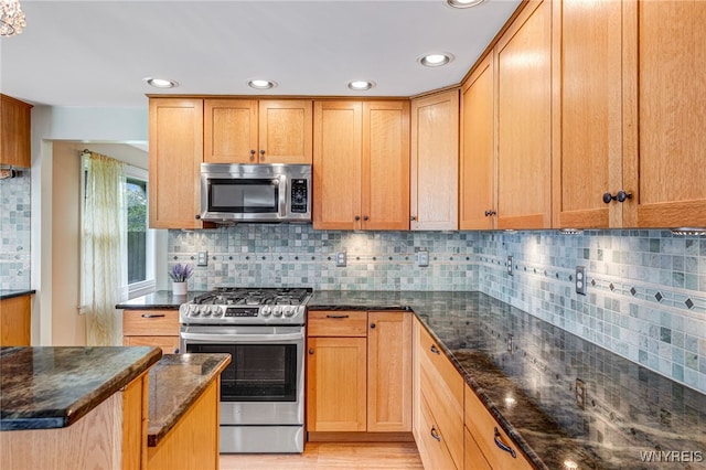 kitchen featuring stainless steel appliances, dark stone countertops, decorative backsplash, recessed lighting, and light wood-style flooring