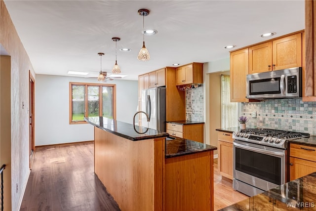 kitchen with stainless steel appliances, backsplash, light wood-style flooring, dark stone countertops, and recessed lighting