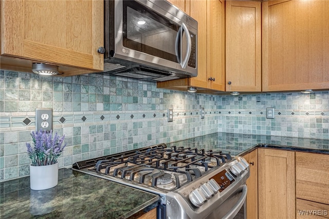 kitchen with stainless steel appliances, tasteful backsplash, and dark stone counters