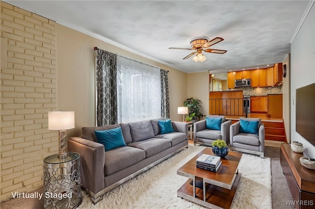 living area with ceiling fan and ornamental molding