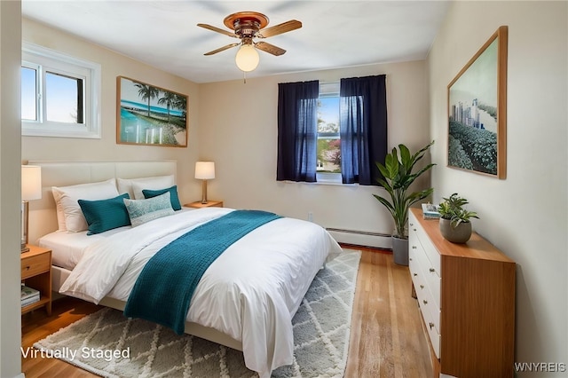 bedroom featuring light wood-style flooring, baseboard heating, and a ceiling fan