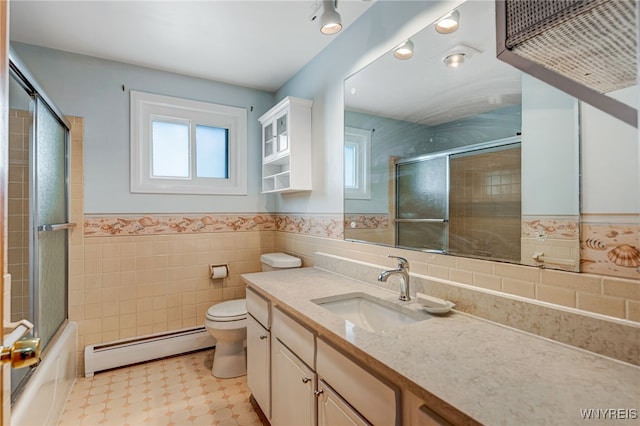 full bath with baseboard heating, plenty of natural light, shower / bath combination with glass door, toilet, and wainscoting