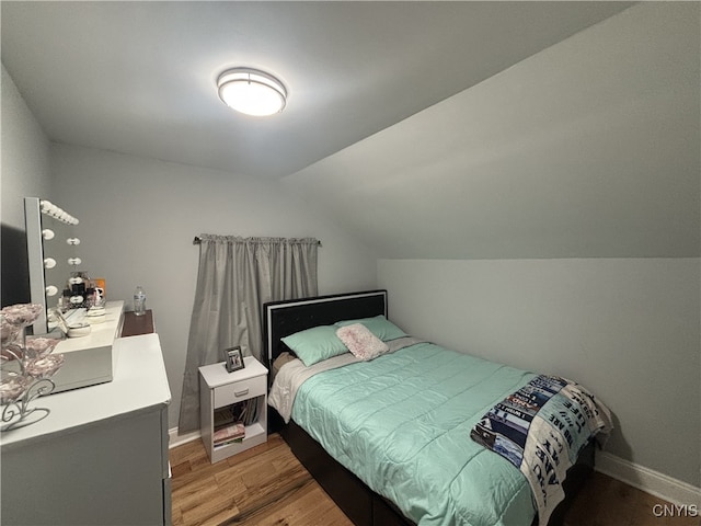 bedroom featuring light wood-type flooring, vaulted ceiling, and baseboards