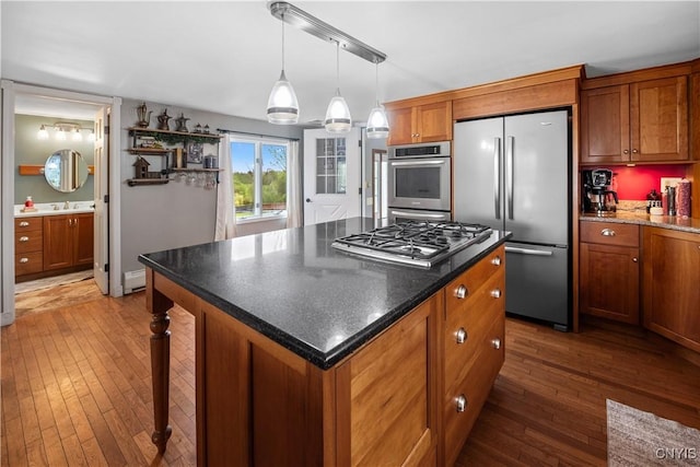 kitchen featuring appliances with stainless steel finishes, dark wood-style flooring, brown cabinets, a baseboard heating unit, and a center island