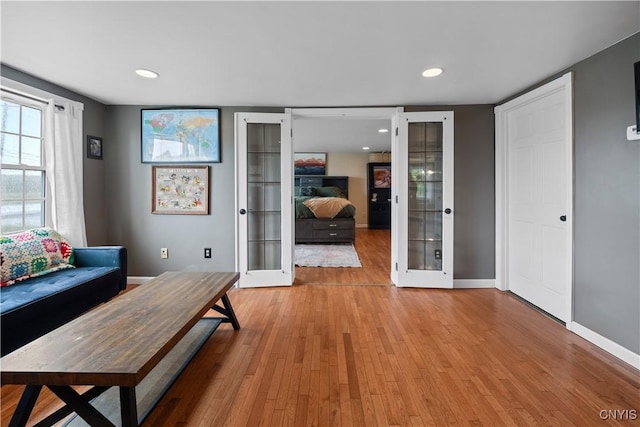 living area with french doors, light wood finished floors, baseboards, and recessed lighting