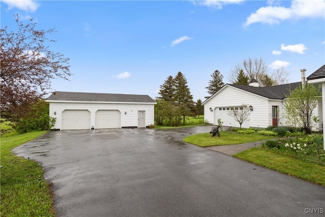 view of side of property with a detached garage and an outbuilding