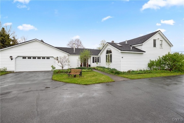 ranch-style house with asphalt driveway, roof with shingles, an attached garage, and a front lawn