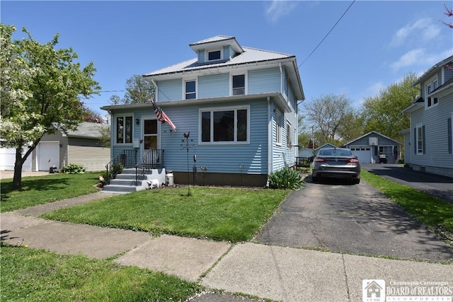 traditional style home with a front lawn, a detached garage, metal roof, and an outdoor structure