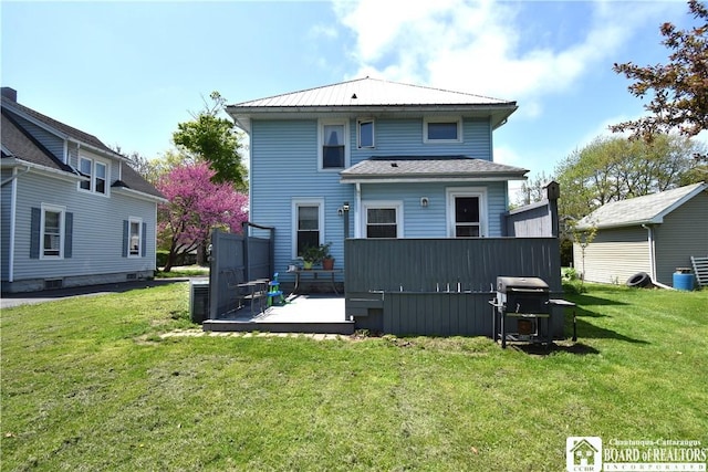 rear view of house featuring a lawn and a deck