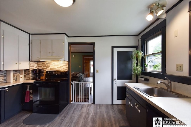 kitchen with black range with electric cooktop, under cabinet range hood, a sink, dark wood-style floors, and crown molding